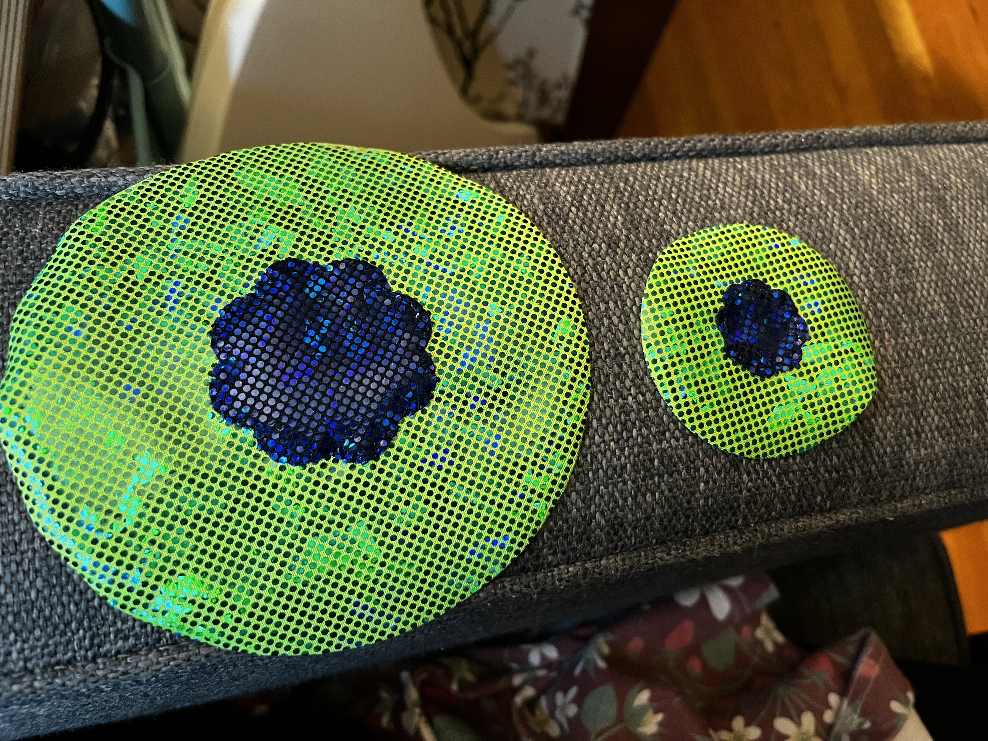 The finished irises. One is about 5” across and the other is about 2.5” across.  Both are bright green sparkly sequin fabric with a black pupil with deep blue microsequins.