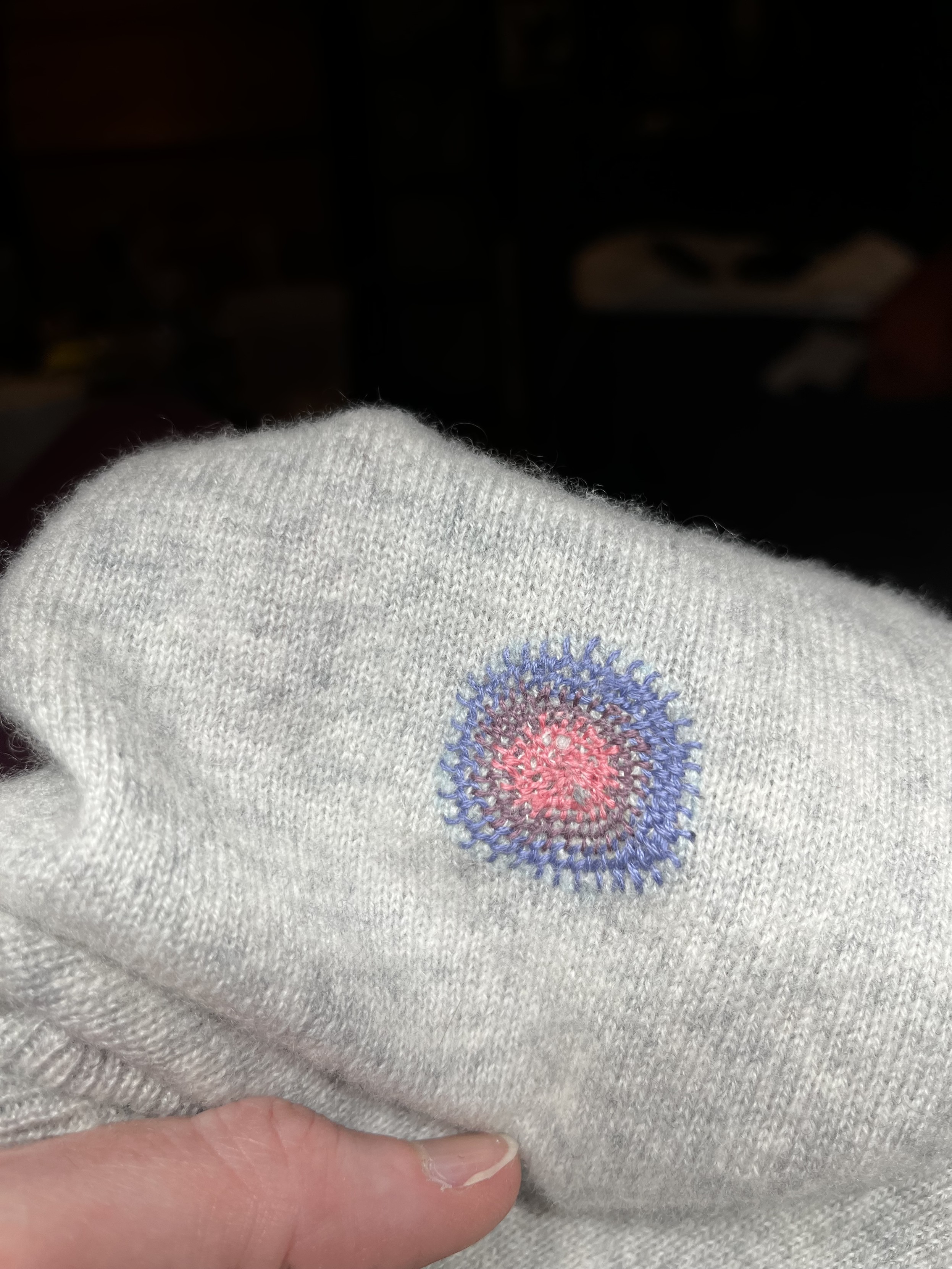 The completed darn is removed from the darning surface. It’s a nice little spot of concentric blue - purple - pink blanket stitch.